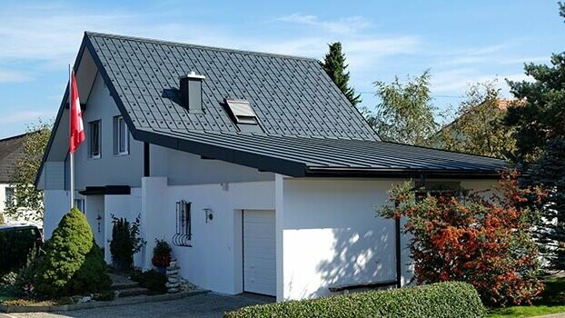 Gerenoveerd huis met zadeldak en aansluitende garage. Het dak werd met de PREFA dakplaat en de garage met Prefalz in antraciet gedekt. Voor het huis staat een vlaggenmast met de Zwitserse vlag.