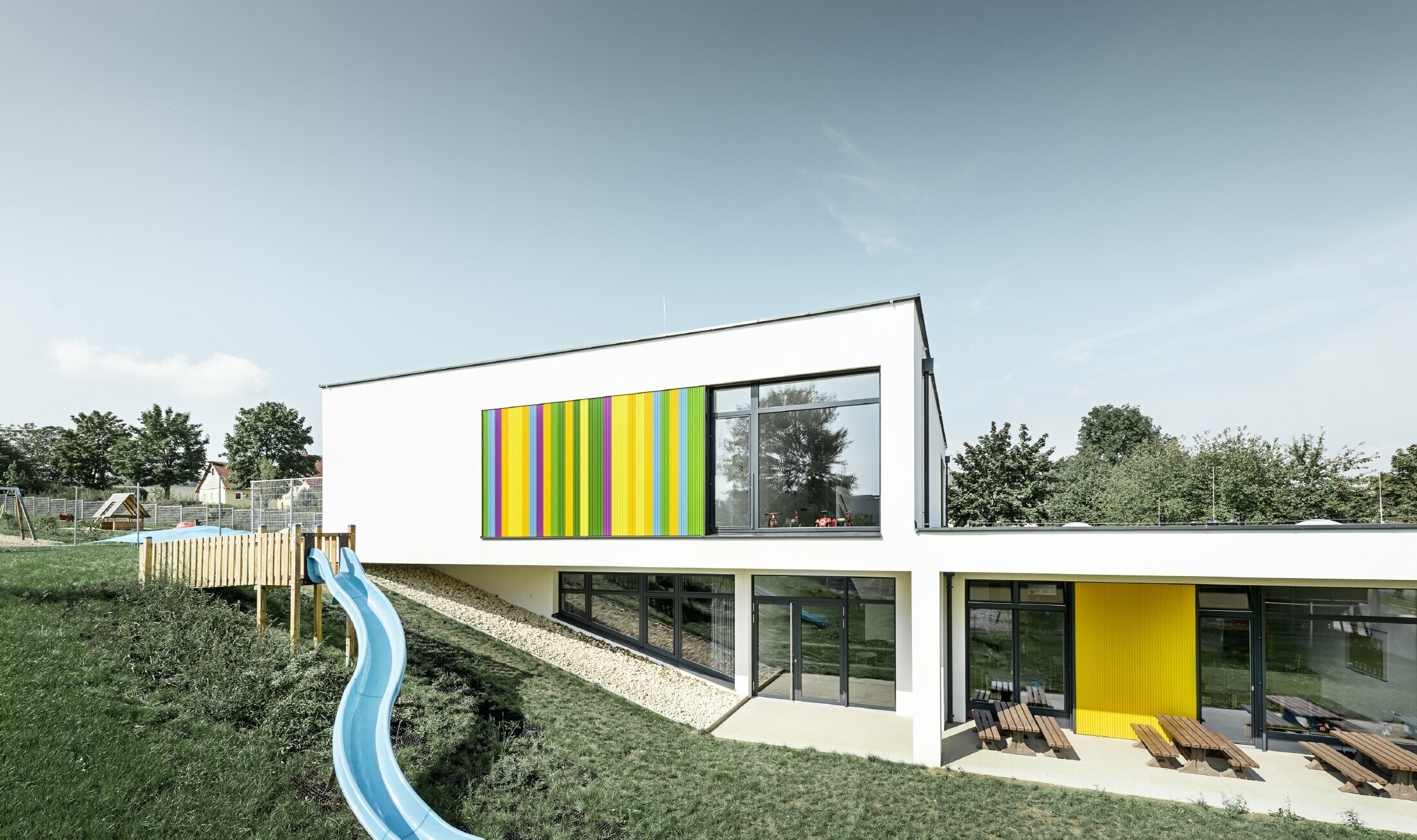 Achteraanzicht van de kleuterschool in Hargelsberg met kleurrijk PREFA kartelprofiel in de kleuren geel, groen, paars en blauw