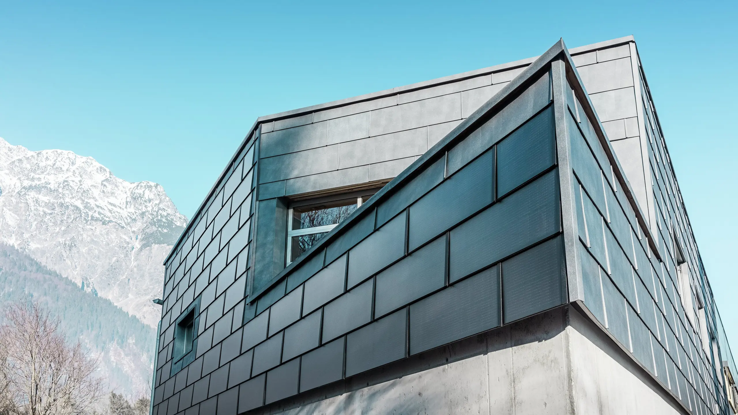 Moderne gevel met de PREFA solar-dakpan: de duurzame aluminium panelen met geïntegreerde fotovoltaïsche cellen wekken stroom op en passen harmonieus in het architectonische ontwerp.
