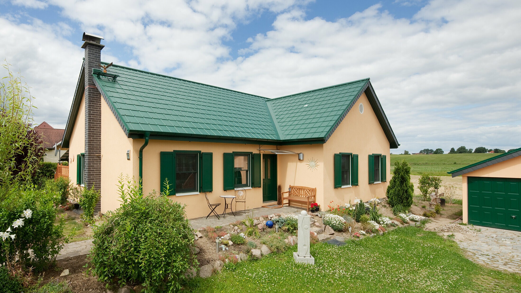 verlengd zadeldak; zadeldak in L-vorm; met PREFA Dakpan in P.10 mosgroen; mooi landelijk huisje met groene luiken passend bij het PREFA dak.