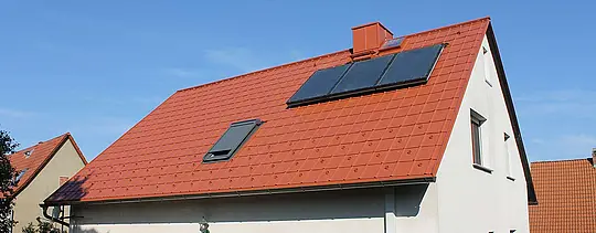 Eengezinswoning met zadeldak bedekt met de PREFA-dakpan in baksteenrood. Dakoppervlak inclusief zonnepanelen en dakraam