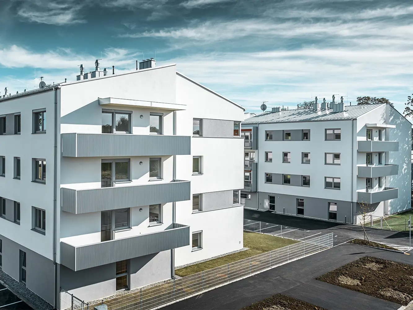 Modern woningcomplex met witte gevel en balkons met PREFA-kartelprofiel in zilvermetallic