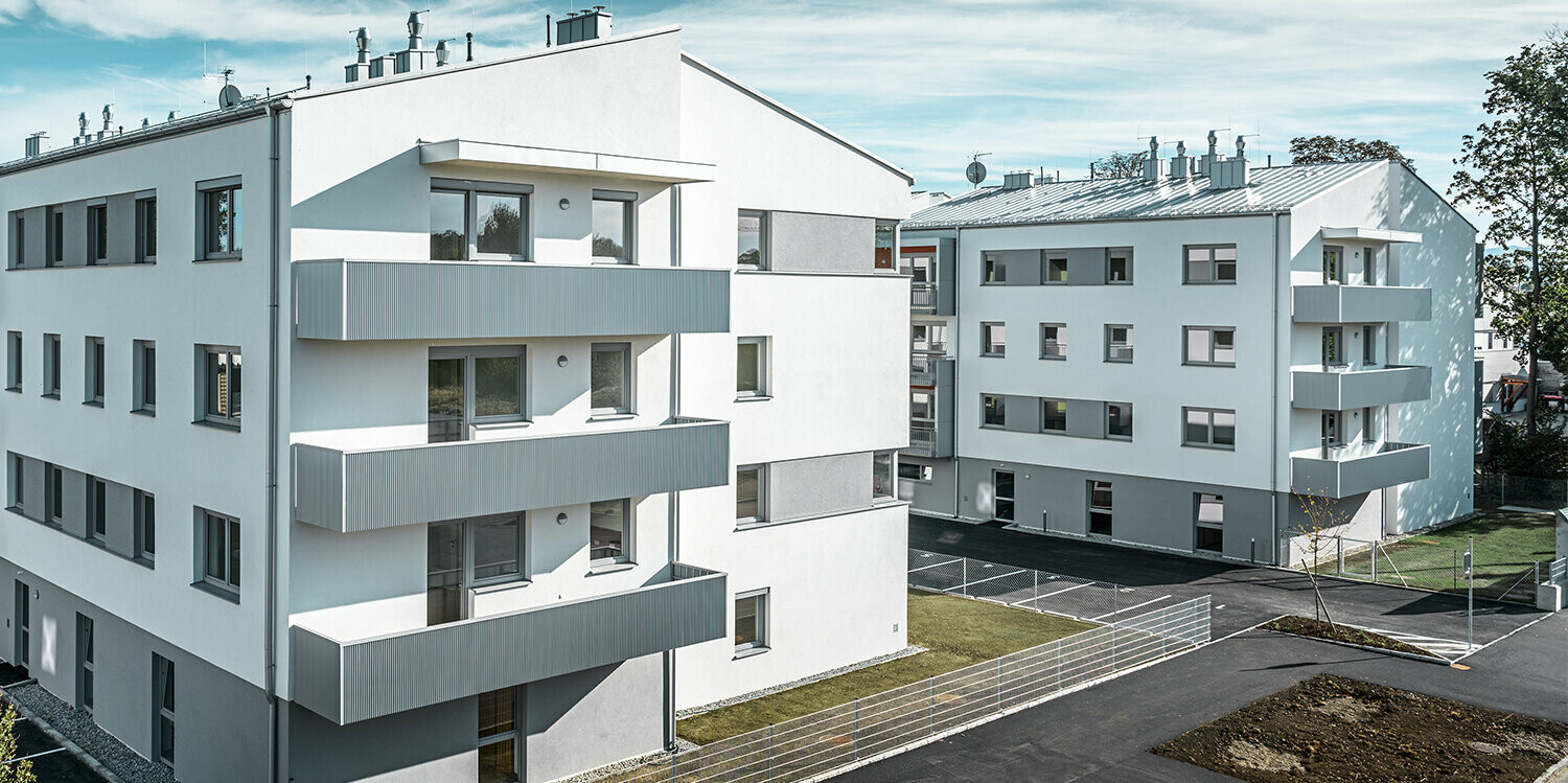 Modern woongebouw met witte gevel en balkons met PREFA kartelprofiel in zilvermetallic