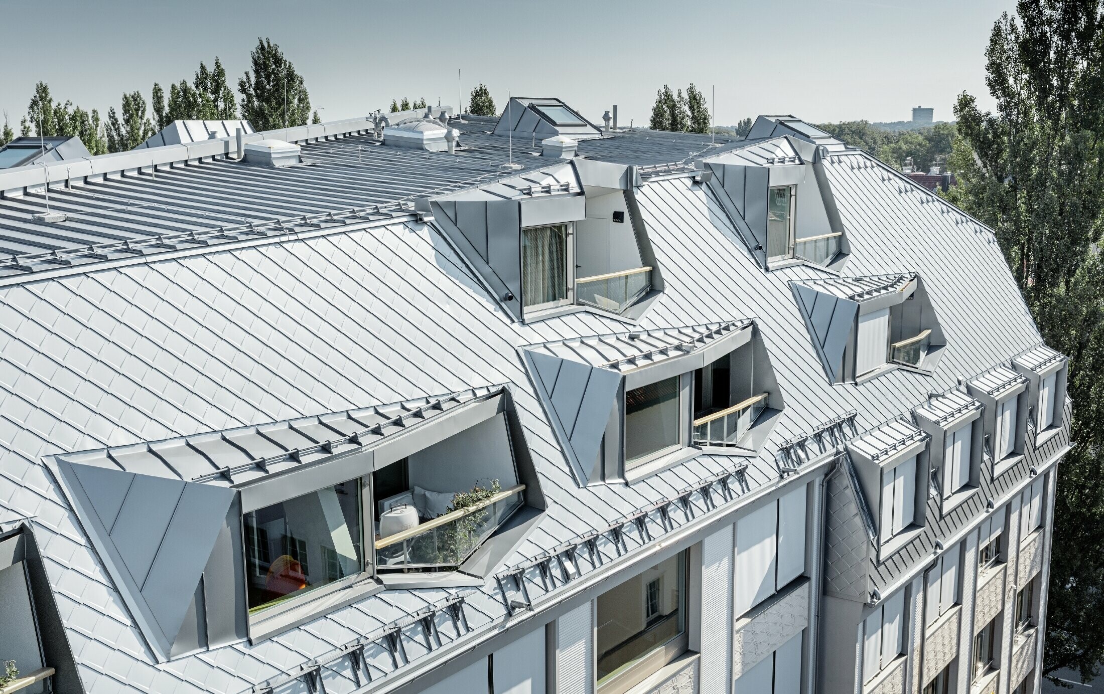 Gerenoveerde dakappartementen met royale loggia's van een woon- en winkelcomplex op de hoek van de Leopoldstraße en Hohenzollernstraße in München. Dakbedekking met PREFA-daklosanges