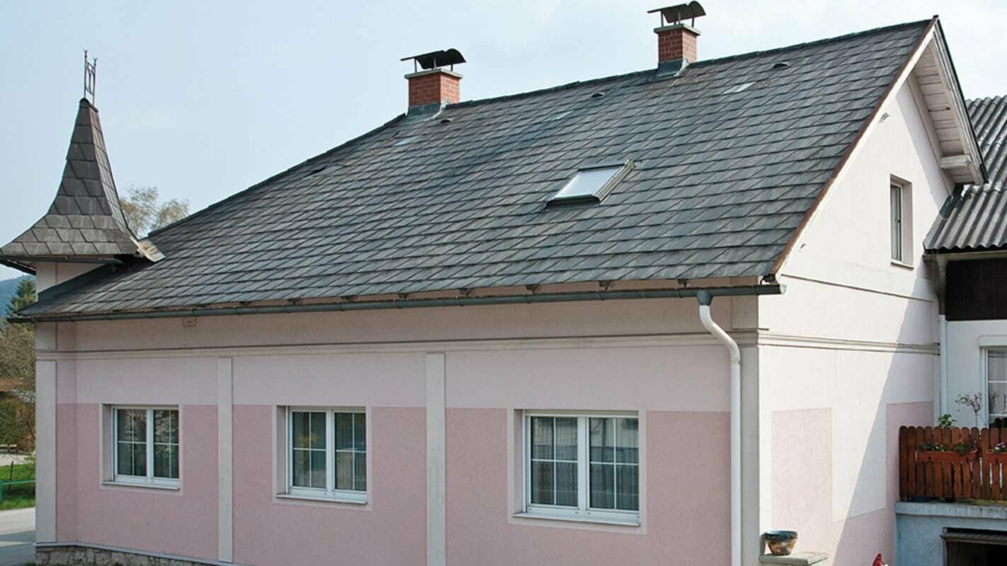 Huis voor de dakrenovatie met de PREFA dakplaat in Oostenrijk - eerder eterniet vezelcement en torentjes, roze gevel