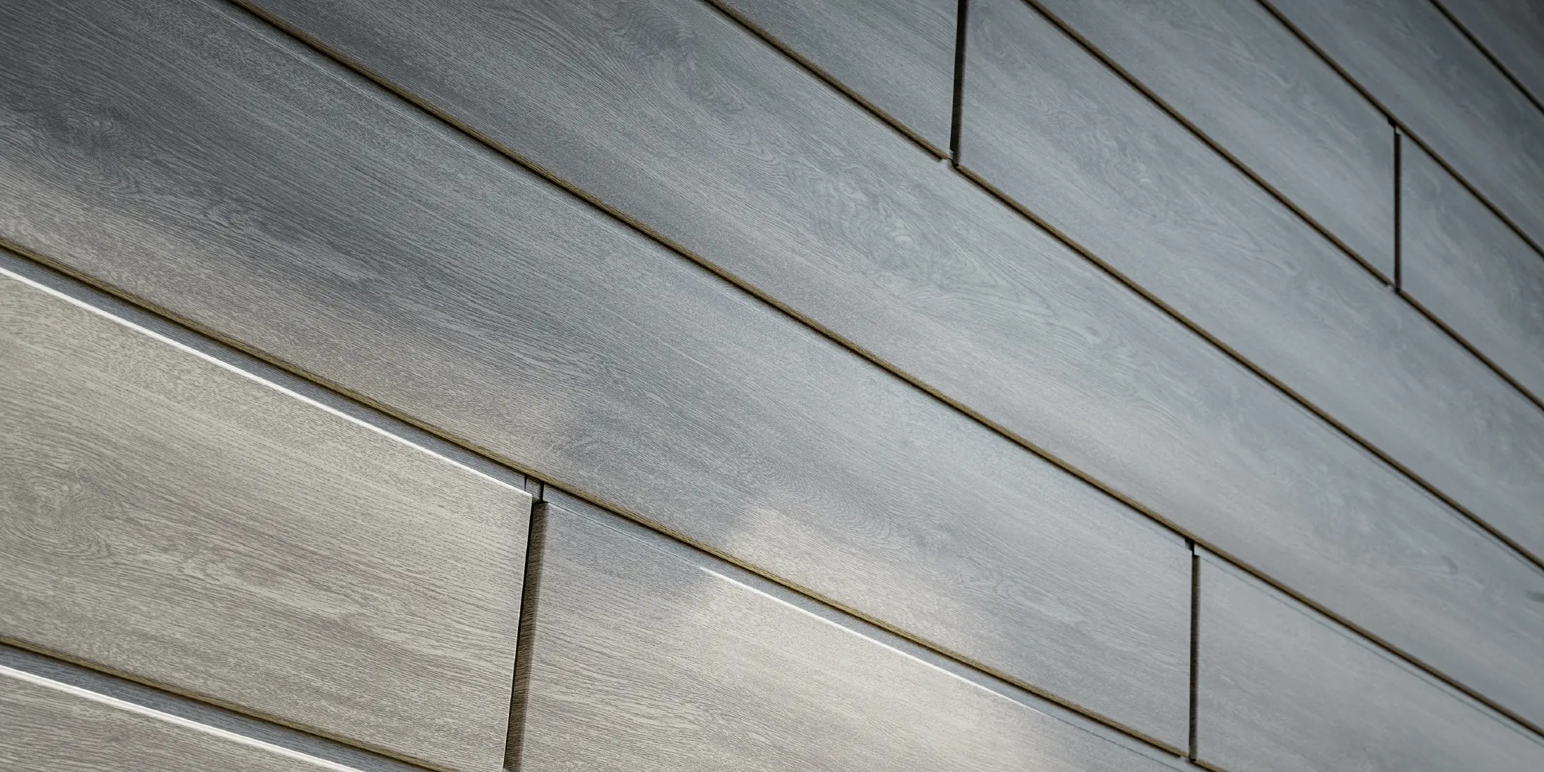 Close-up van de PREFA Sidings aluminium gevel, de aluminium panelen zijn horizontaal geplaatst en hebben een houtlook - grijs eiken.