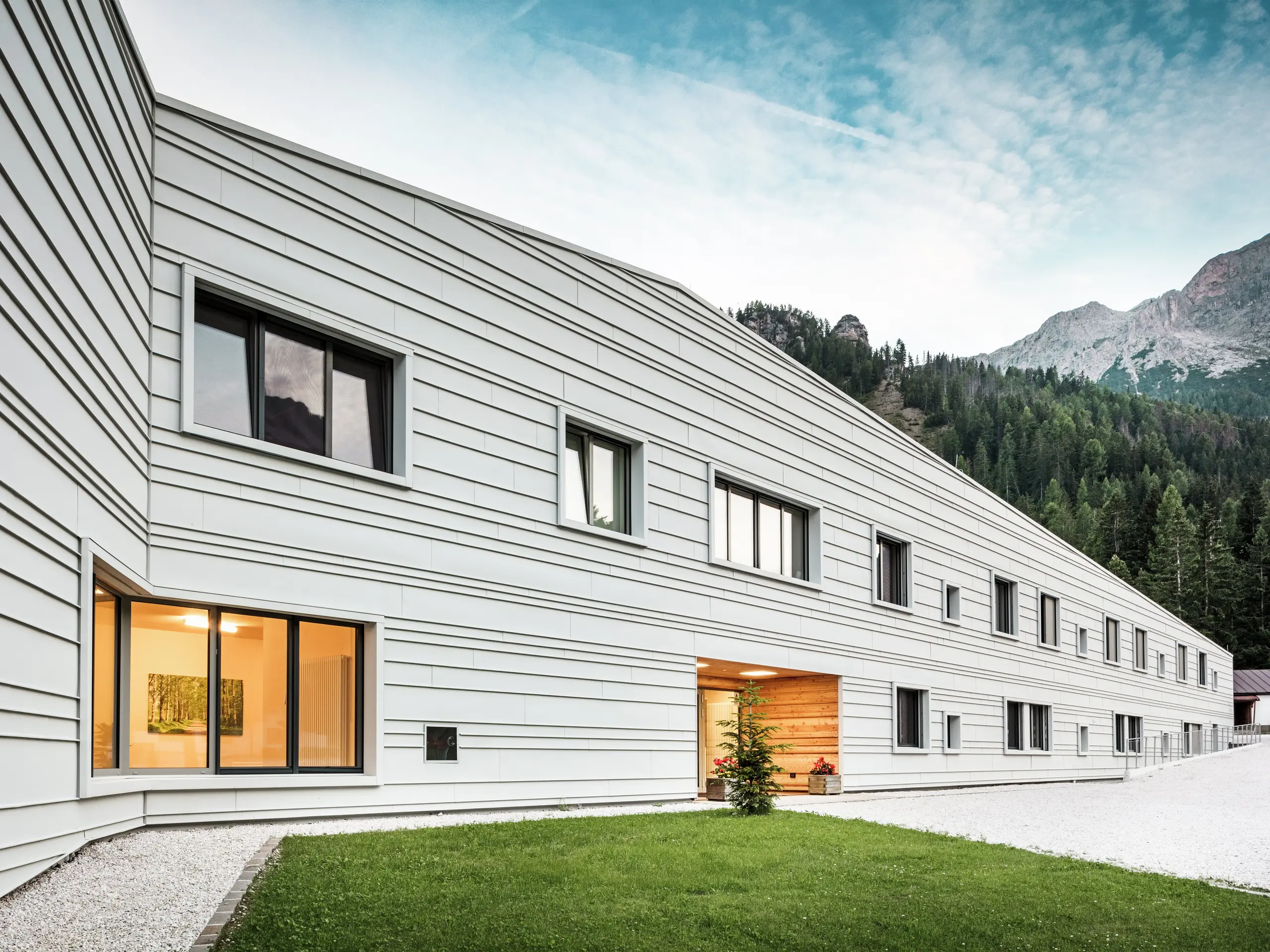 Die moderne Kaserne „Tempesti“ in Südtirol besticht durch ihre klare Fassadengestaltung aus PREFALZ P.10 in der Farbe Prefaweiß. Horizontal und unregelmäßig angeordnete Aluminiumstreifen lassen das Gebäude länger wirken. Die helle Aluminiumfassade reflektiert das Sonnenlicht und verbessert so das Raumklima. Diese moderne Kaserne ist ein architektonisches Highlight inmitten der Alpenlandschaft.