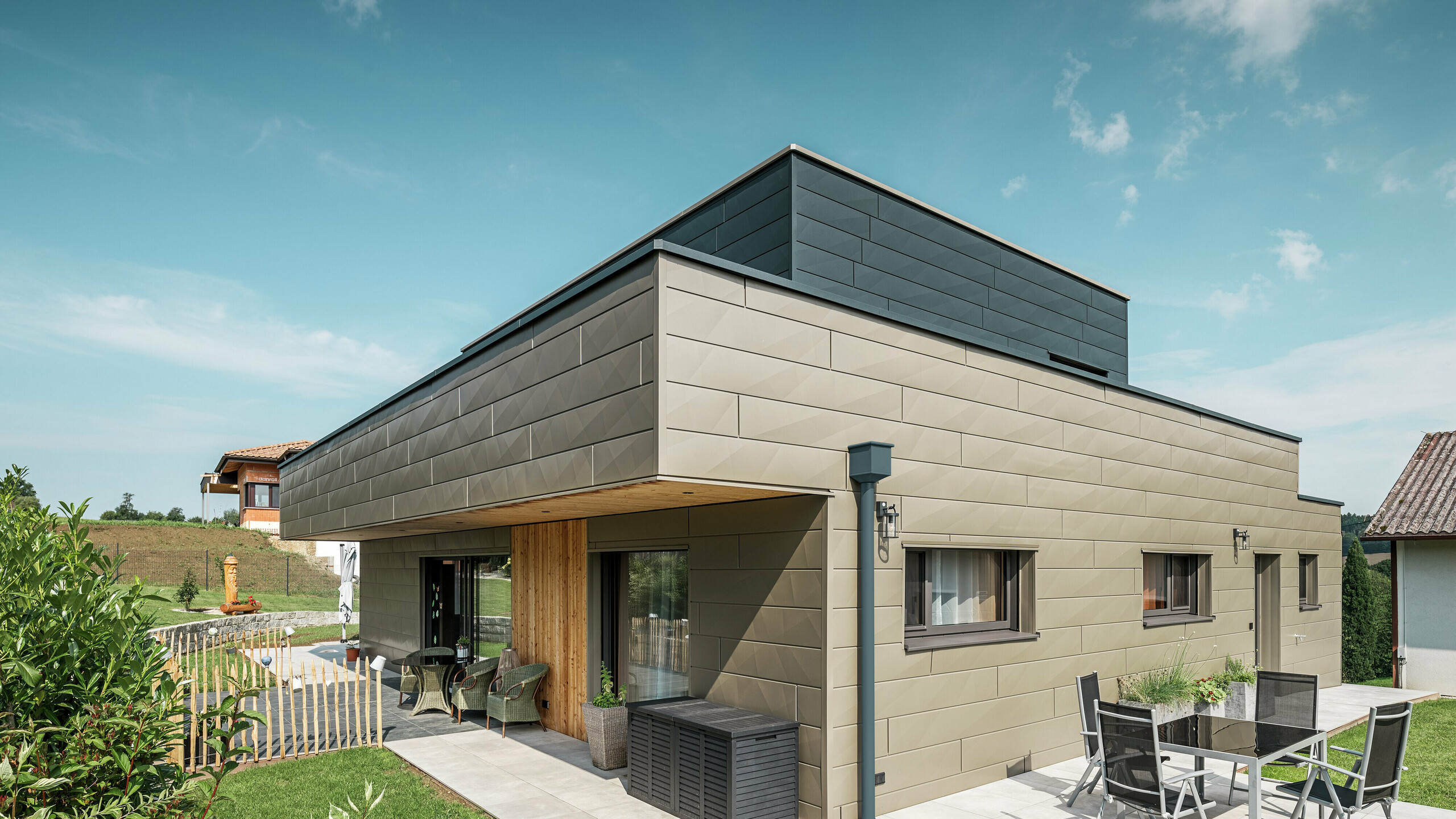 Te zien is een vrijstaand huis in Wippenham met een tweekleurige gevel gemaakt van Siding.X in de kleuren P.10 Prefabrons en P.10 Antraciet.