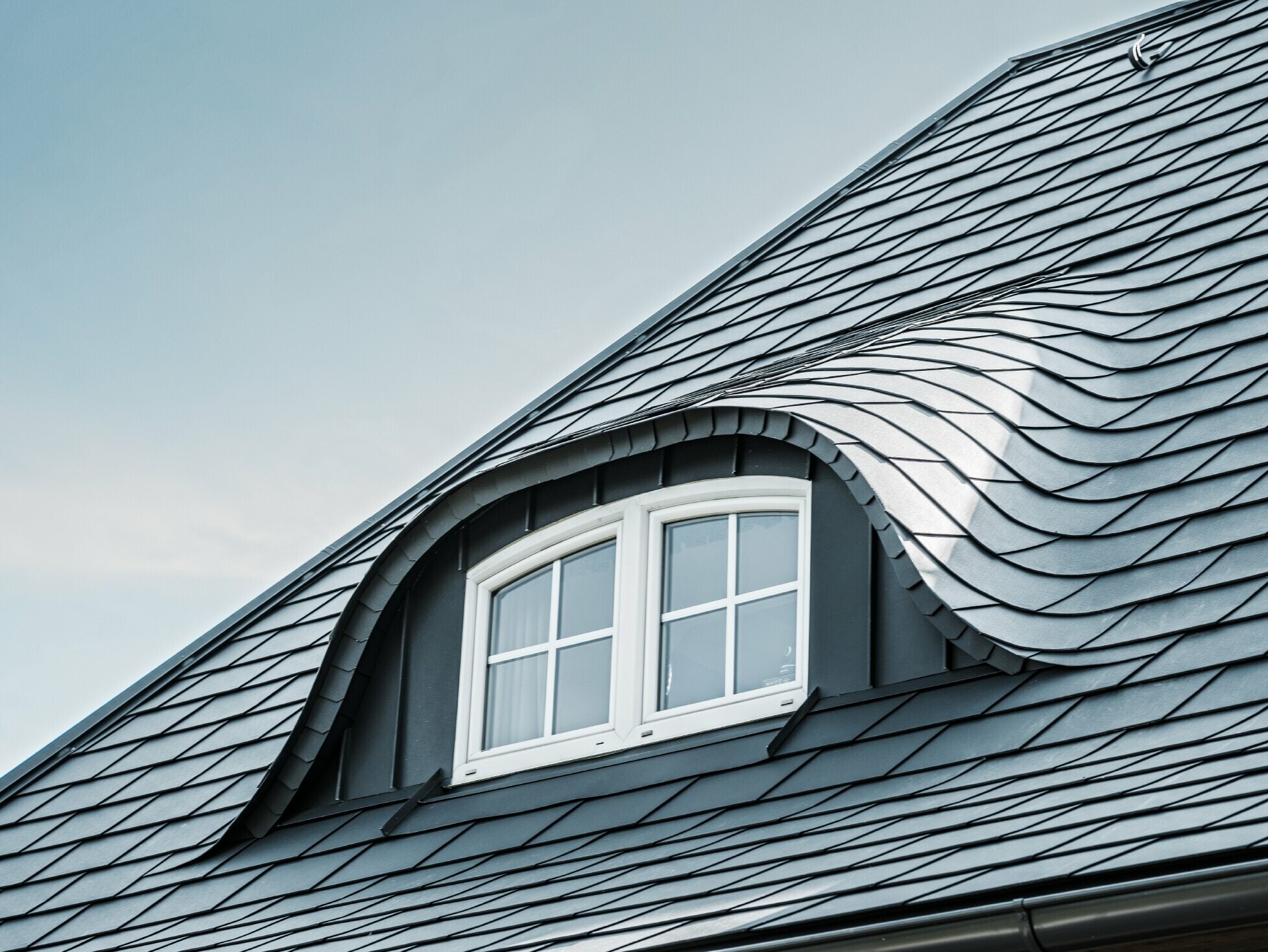 Gerenoveerd dak met gebogen dakkapel met raam, bekleed met aluminium schindels van PREFA in P.10 antraciet