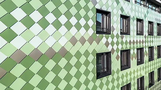Moderne PREFA-Fassadenverkleidung mit PREFA-Rhombusen in den speziell entwickelten Sonderfarben Olivgrün, Graugrün, Resedagrün, Opalgrün, Hellelfenbein, Perlweiß und Hellbronze. Das Wohn- und Geschäftsgebäude „Pick-Nick“ in Dresden besticht durch seine einzigartige Ästhetik, Witterungsbeständigkeit, Langlebigkeit und Wartungsfreiheit. Das stilvolle Design und die Farbvielfalt setzen architektonische Akzente und bieten nachhaltigen Schutz.