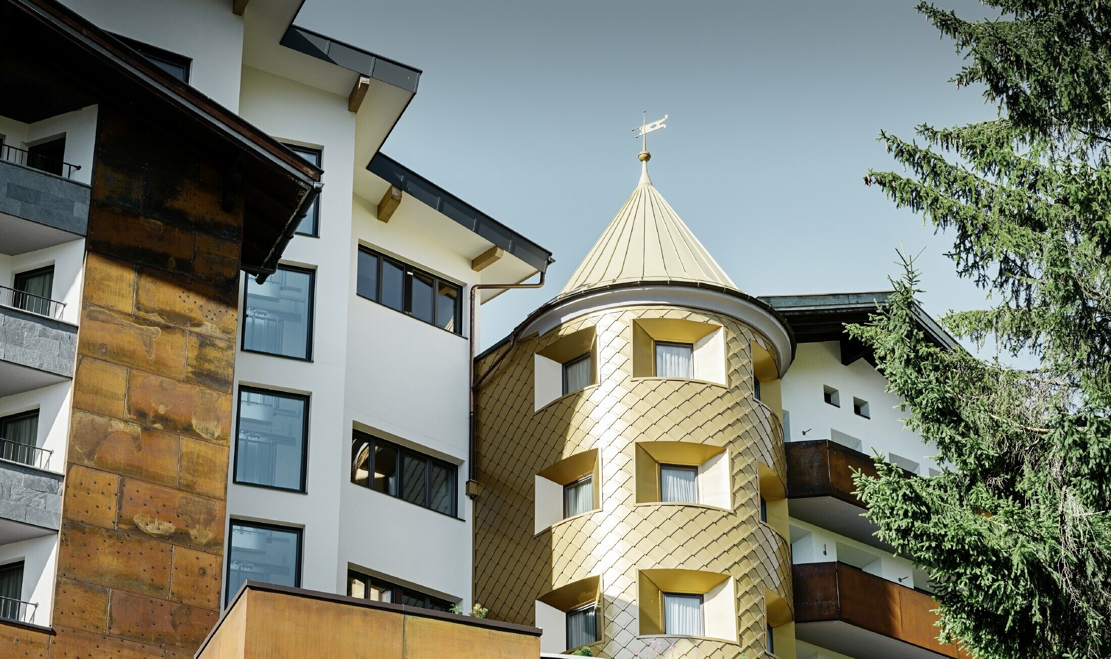 Traditioneel hotel in Ischgl (Oostenrijk) met houten balkonns en gevel en een toren met gouden aluminiumlosanges van PREFA