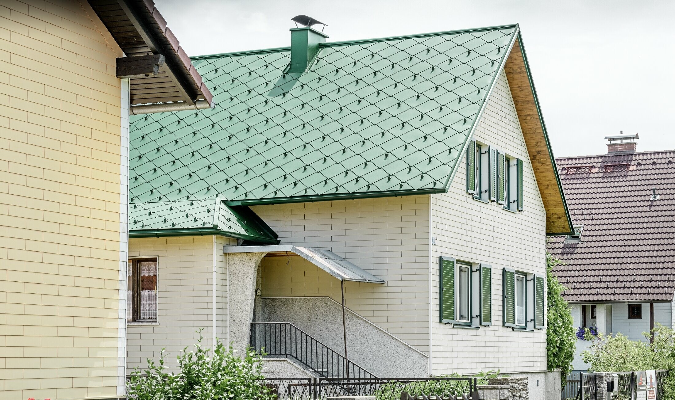 Klassieke alleenstaande woning met zadeldak bedekt met mosgroene aluminium daklosanges, in harmonie met de groene vensterluiken