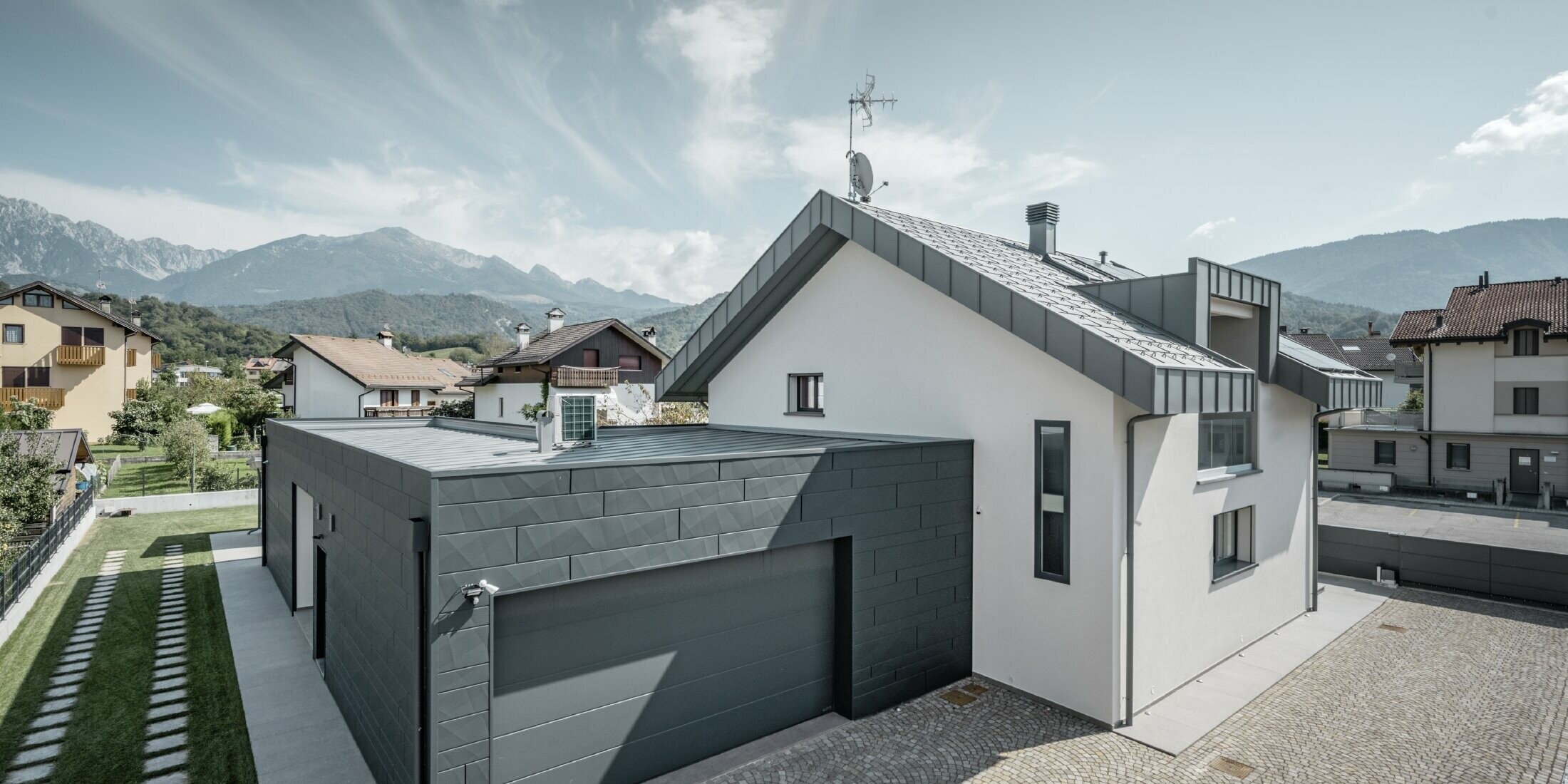 Foto vom Einfamilienhaus, die Garage ist mit Siding.X gedeckt, das Dach ist in R.16 in der Farbe P.10 hellgrau gedeckt.