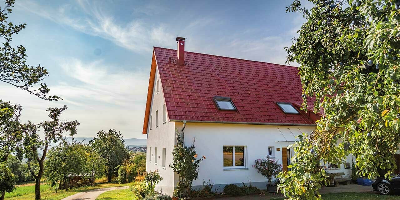 Romantisch huisje op het land met veel bomen en struiken. Gedekt met een PREFA dak in oxiderood.