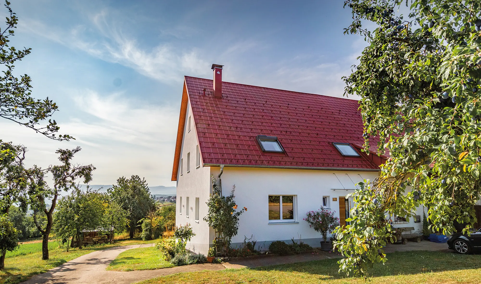 Romantisch huisje op het land met veel bomen en struiken. Gedekt met een PREFA dak in oxiderood.