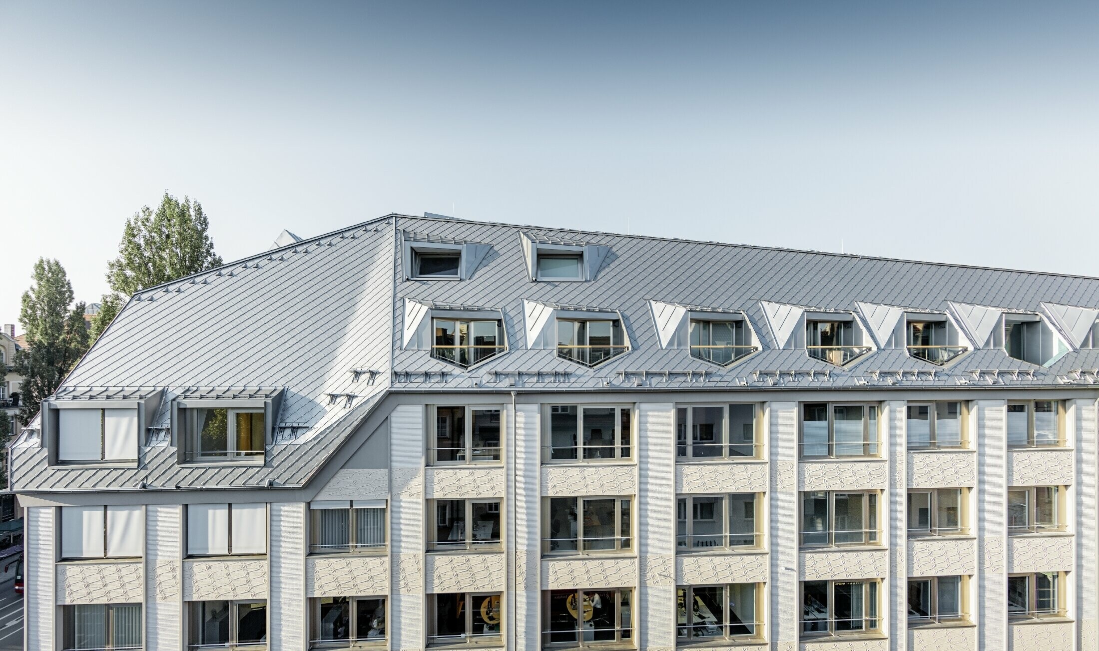 Gerenoveerde dakappartementen met royale loggia's van een woon- en winkelcomplex op de hoek van de Leopoldstraße en Hohenzollernstraße in München. Dakbedekking met PREFA-daklosanges
