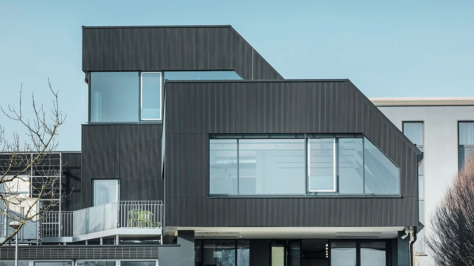 Zijaanzicht van het gebouw van Amann Kaffee op een zonnige dag Ter bescherming van het gebouw werd een gekarteld profiel in de kleur zwart gebruikt.
