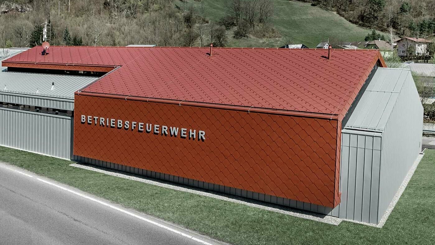 De nieuwe brandweerkazerne van de bedrijfsbrandweer van PREFA en Neuman Aluminium werd bekleed met de nieuwe dak- en gevellosange van 44 × 44 in P.10 oxiderood, alsmede Prefalz in zilvermetallic.