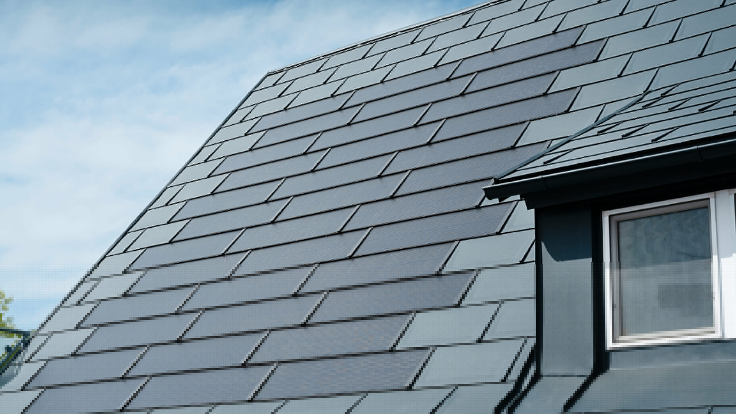 Detailopname van het gerenoveerde dak van een eengezinswoning in Leonding met PREFA-zonnedakpanelen in antraciet. De close-up toont de hoogwaardige aluminium panelen van PREFA, die een naadloze integratie van de zonnepanelen mogelijk maken. Deze duurzame en weerbestendige oplossing biedt een duurzame en energie-efficiënte manier om stroom op te wekken. De foto illustreert de esthetische en functionele kwaliteit van de gebruikte materialen. Rechts op de foto is een wit raam onder een slepende dakkapel te zien.