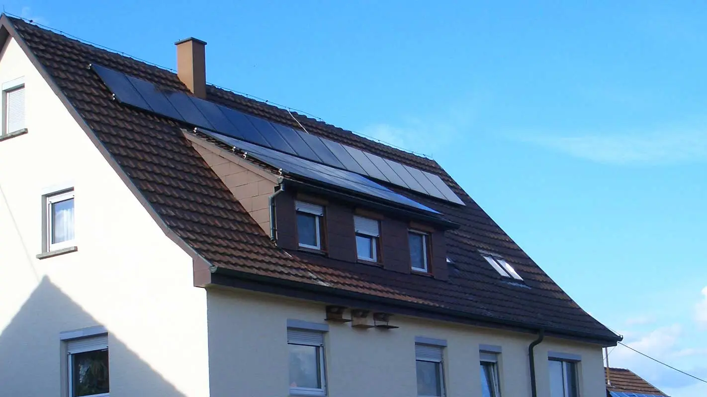 Eengezinswoning met dakpannendak dat moet worden gerenoveerd; het dak heeft een koekkoek en een fotovoltaïsche installatie.