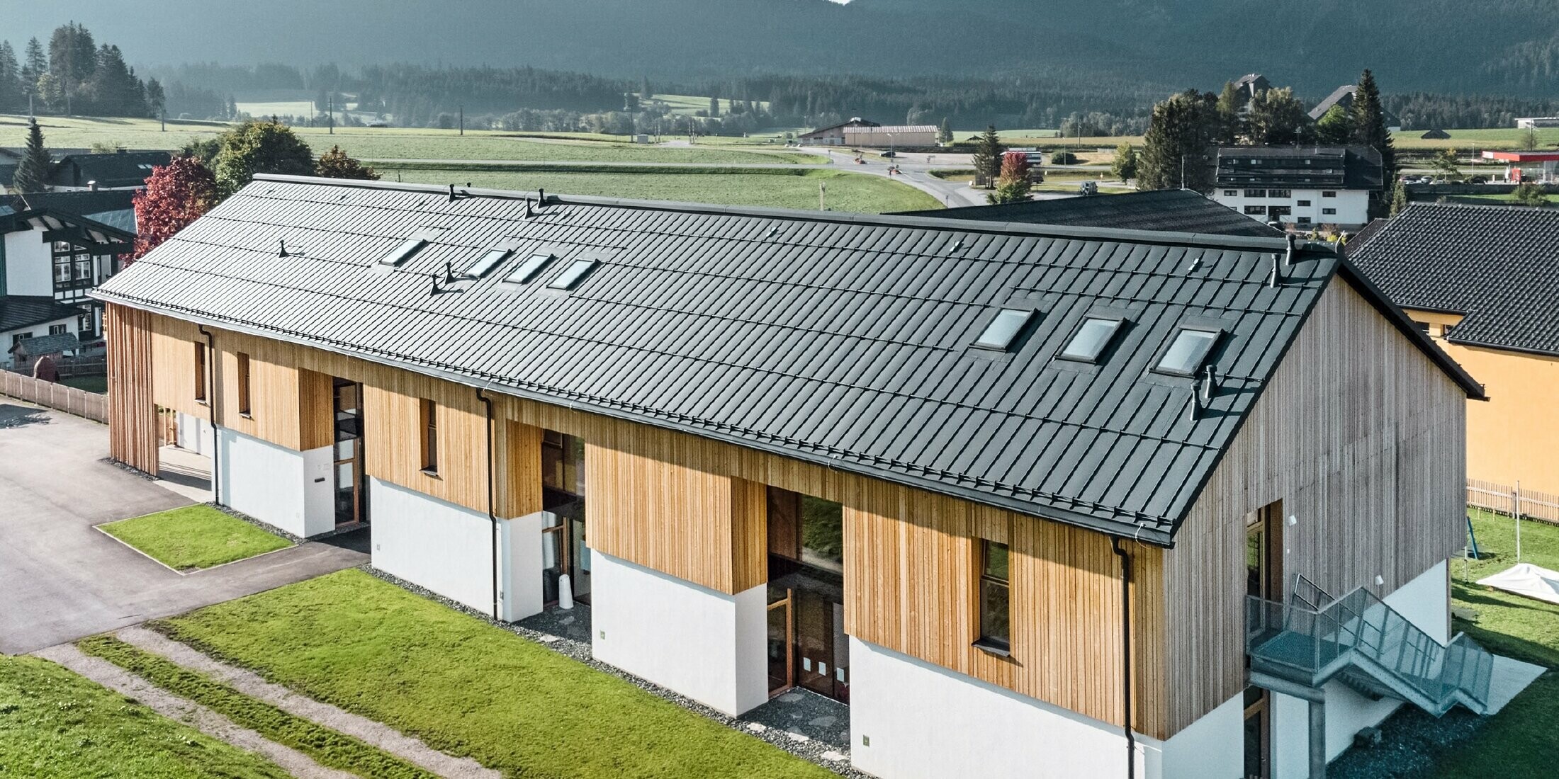 Kruidenkleuterschool in Bad Mitterndorf met groot PREFALZ dak in P.10 antraciet en houten gevel