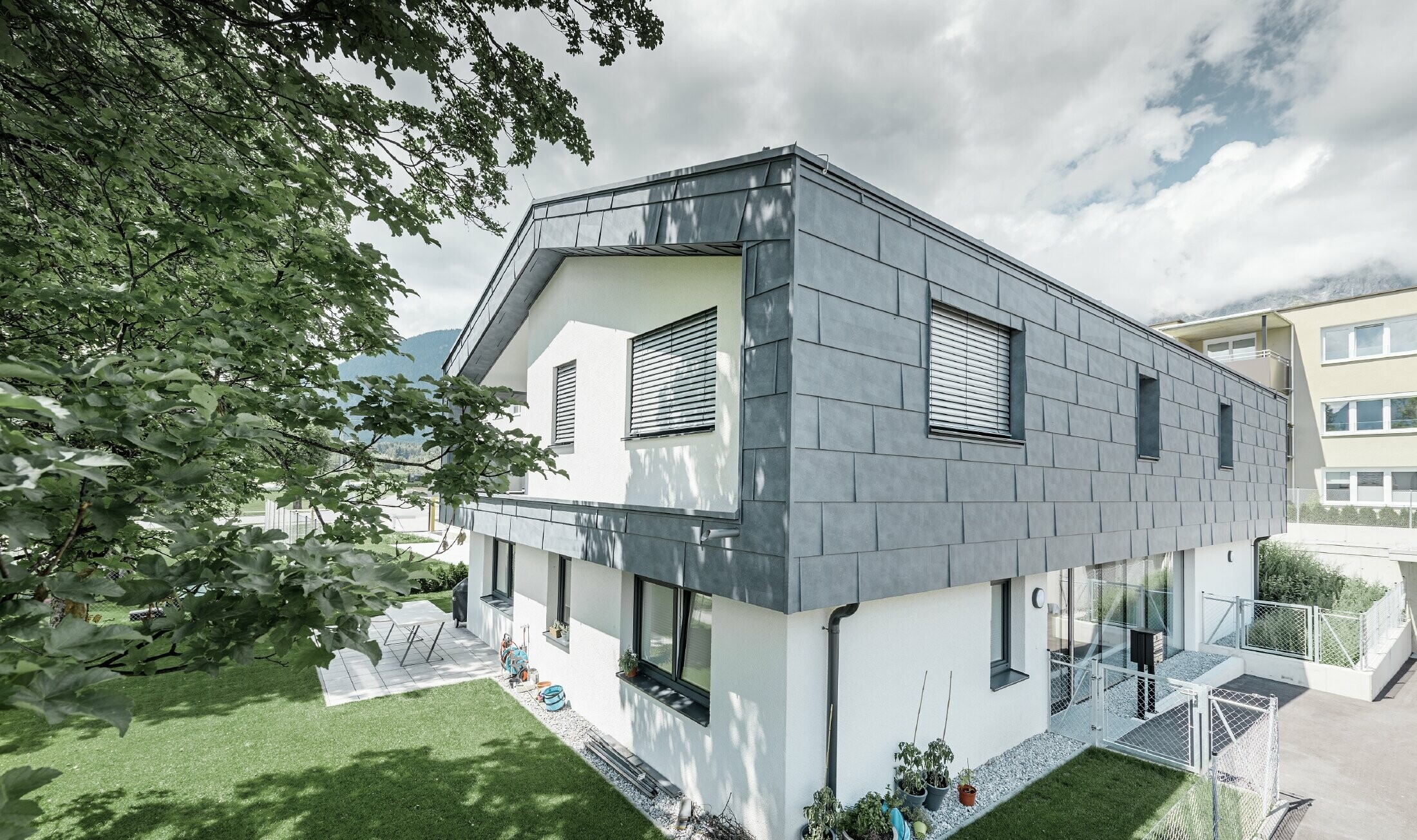 Moderne verhoging van een woonhuis met plat zadeldak en zonder dakoverstek; De gevelbekleding is uitgevoerd met het PREFA gevelpaneel FX.12 in steengrijs.