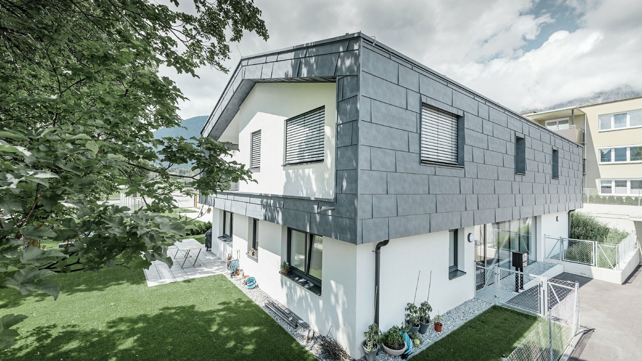 Moderne verhoging van een woonhuis met plat zadeldak en zonder dakoverstek; De gevelbekleding is uitgevoerd met het PREFA gevelpaneel FX.12 in steengrijs.