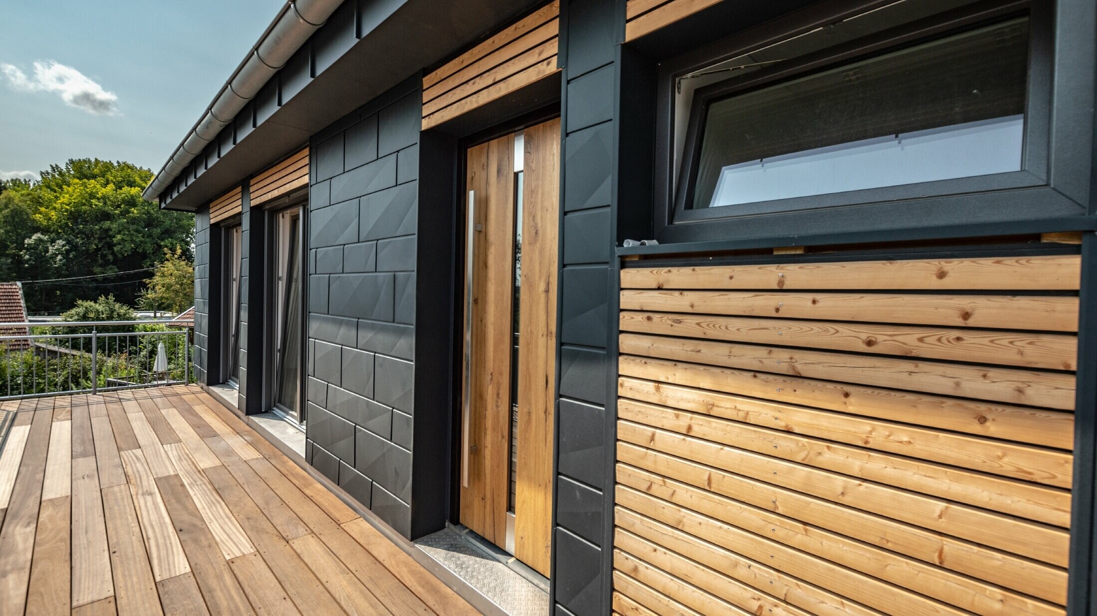 Gevelvormgeving door een materiaalmix aluminium - PREFA Siding.X in antraciet - en horizontale houten lijsten.