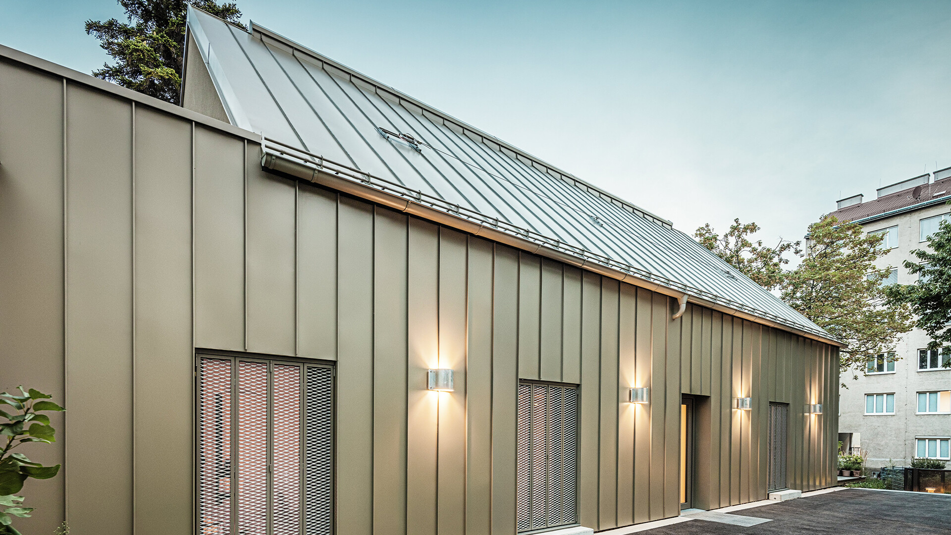 De foto toont een close-up van Atelier Comploj met een gevel en dak gemaakt van PREFALZ in de kleur P.10 Prefabrons.