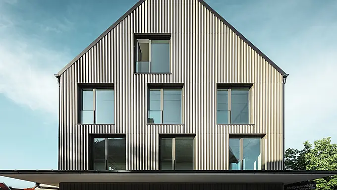 Das Bild zeigt ein modernes Gebäude in Feldkirch, entworfen vom Architekten Stefan Heigl. Die Fassade ist mit Prefalz in der Farbe Bronze verkleidet, während das Satteldach mit Prefalz in Schwarzgrau gedeckt ist. Große, rechteckige Fenster sorgen für viel Tageslicht im Inneren. Das Gebäude kombiniert hochwertige Materialien und eine elegante Architektur, die sowohl funktional als auch ästhetisch ansprechend ist. Diese moderne Bauweise und die Verwendung von Prefalz Materialien verleihen dem Gebäude ein zeitgemäßes und stilvolles Erscheinungsbild.