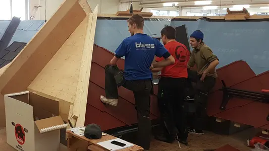 PREFA Lehrverleger zeigt in der PREFA Academy einem Teilnehmer die richtige Verlegung der PREFA Produkte.
