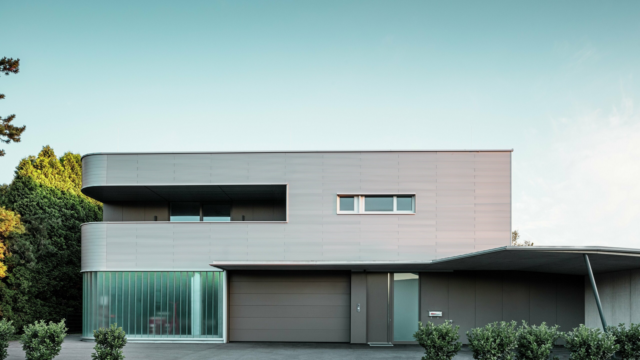 Modern woongebouw met PREFA golfplaatgevel in blank naturel met garage.