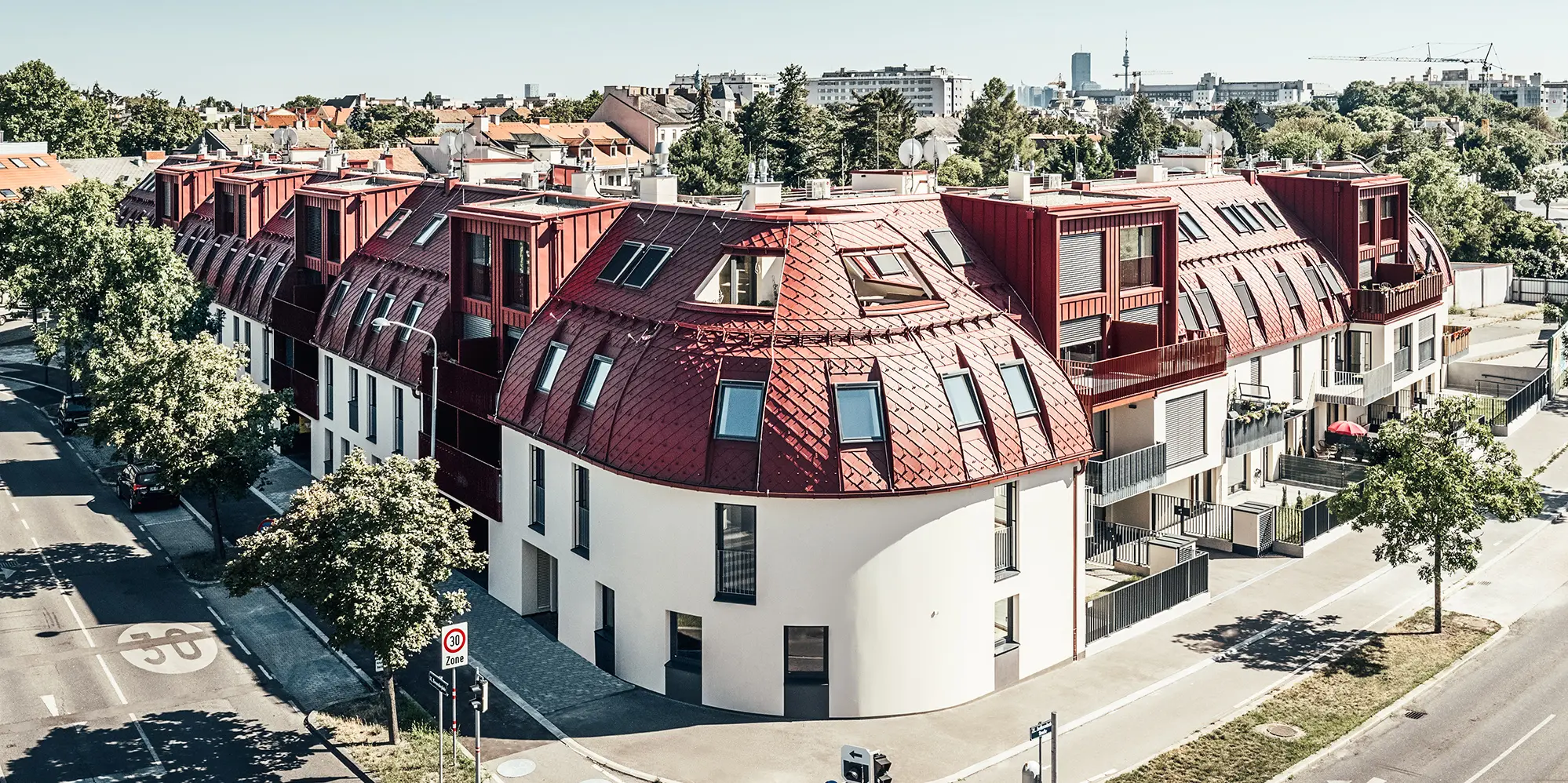 Straatbeeld van het wooncomplex Schöneck 13 en het afgeronde daklandschap, ontworpen door architectenbureau schneider+schumacher.