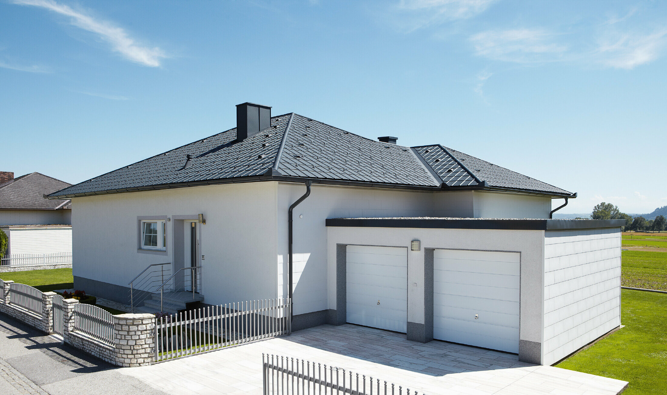 De nieuw gebouwde bungalow met tentdak werd bedekt met PREFA-dakpan in P.10 antraciet. Rechts werd een dubbele garage toegevoegd, gefotografeerd vanaf de straat.