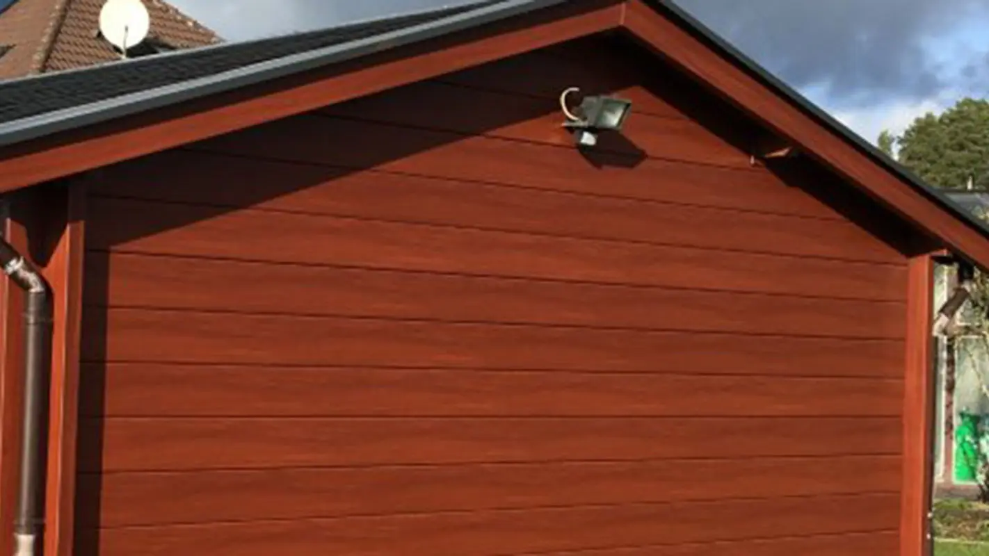 Gerenoveerd tuinhuis met een nieuwe muurbekleding in hout-look, daarvoor was het bekleed met hout, nu met de PREFA gevelbeplating in een donkere houttint 