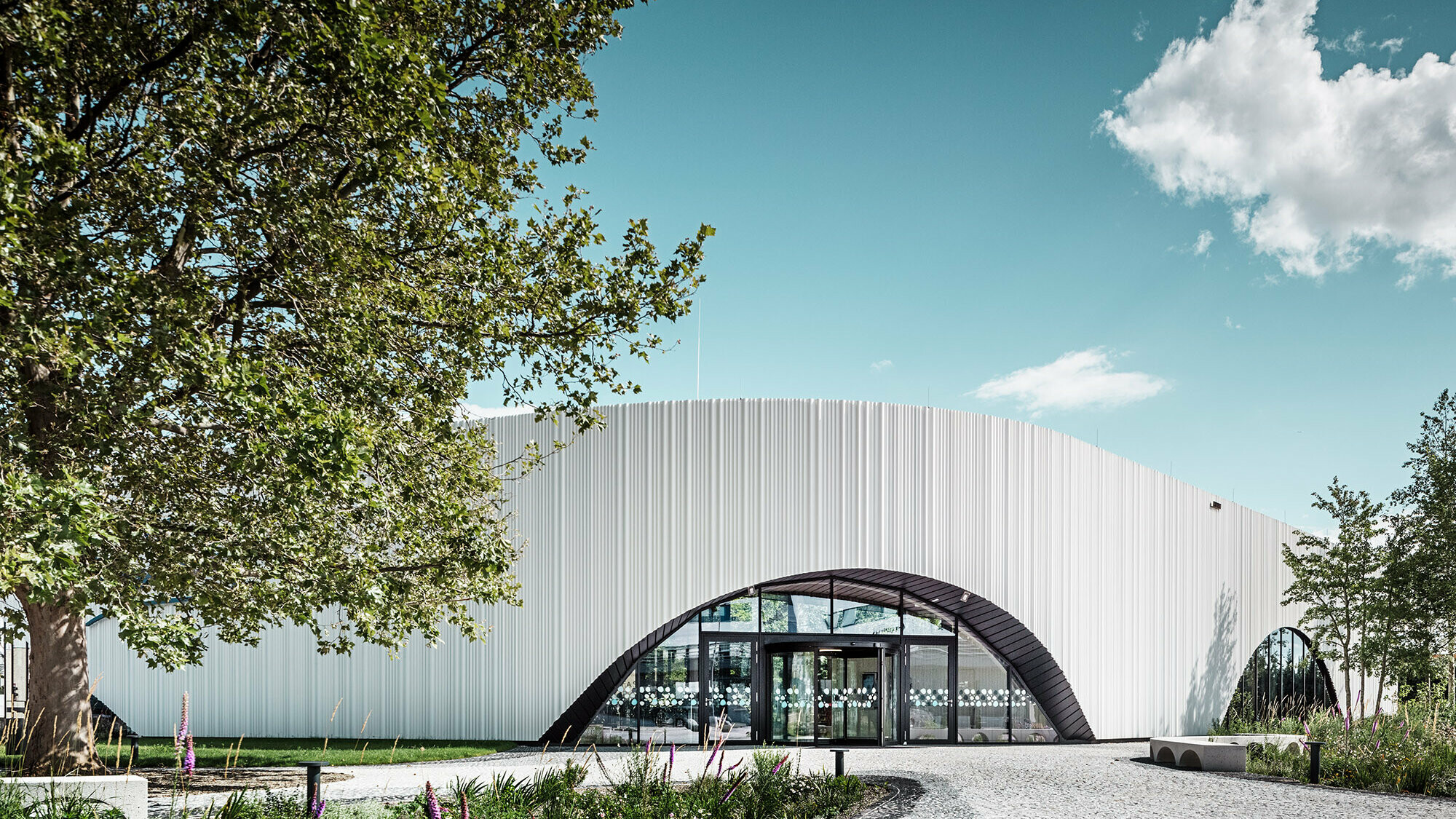 Normaal aanzicht van het restaurant Walter met één van zijn ronde boogramen in het midden van een groene omgeving.