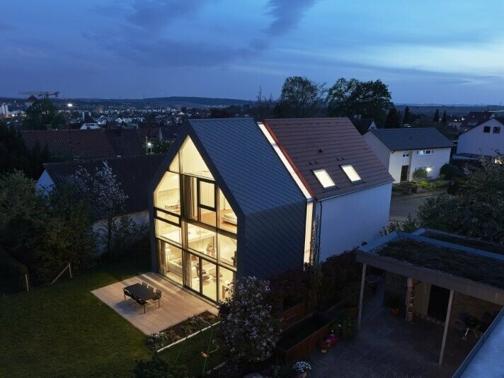 seitliche Ansicht des Haus J in Stuttgart (Deutschland) bei Nacht. Das Haus J wurde mit der Dachraute 29 × 29 in der Farbe P.10 Hellgrau verkleidet.