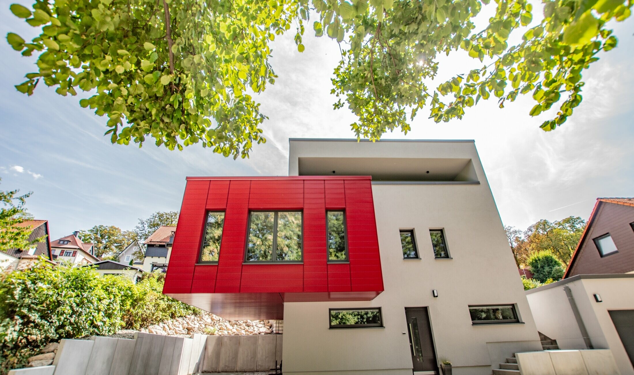 Uitstekend gebouwdeel met de PREFA sidings in robijnrood bekleed. Grote, rode erker die zich onderscheidt van de gevel.