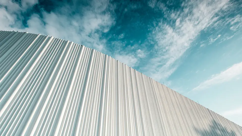 Atemberaubende Architektur mit weißer PREFA Aluminiumfassade im Walter Business-Park bei Wien. Die Fassade aus maßgefertigten Individualprofilen erzeugt durch ihren fließenden Wellencharakter ein faszinierendes Spiel aus Licht und Schatten. Drei unterschiedliche Profilformen sorgen für eine außergewöhnliche Tiefenwirkung und verleihen dem Gebäude eine stilistisch klare und zugleich dynamische Optik. Die langlebige, witterungsbeständige PREFA Oberfläche kombiniert moderne Ästhetik mit funktionaler Perfektion – ein echtes Highlight zeitgenössischer Fassadengestaltung, das architektonische Qualität und technische Raffinesse sichtbar macht.