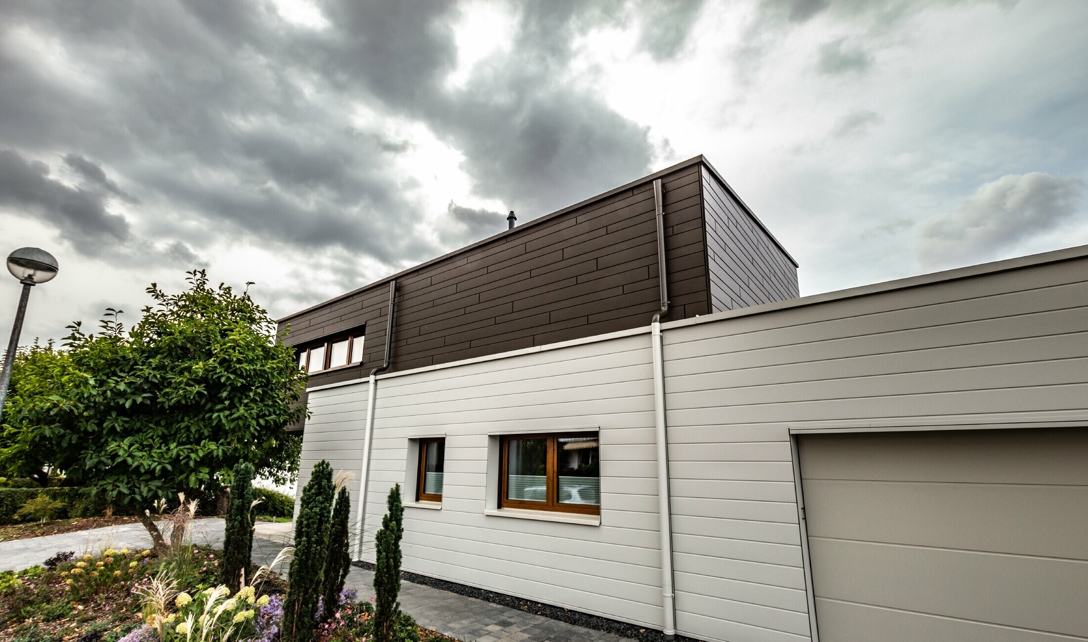 Gevelbekleding van een garage met de PREFA sidings horizontaal in wit, met spuwermond.