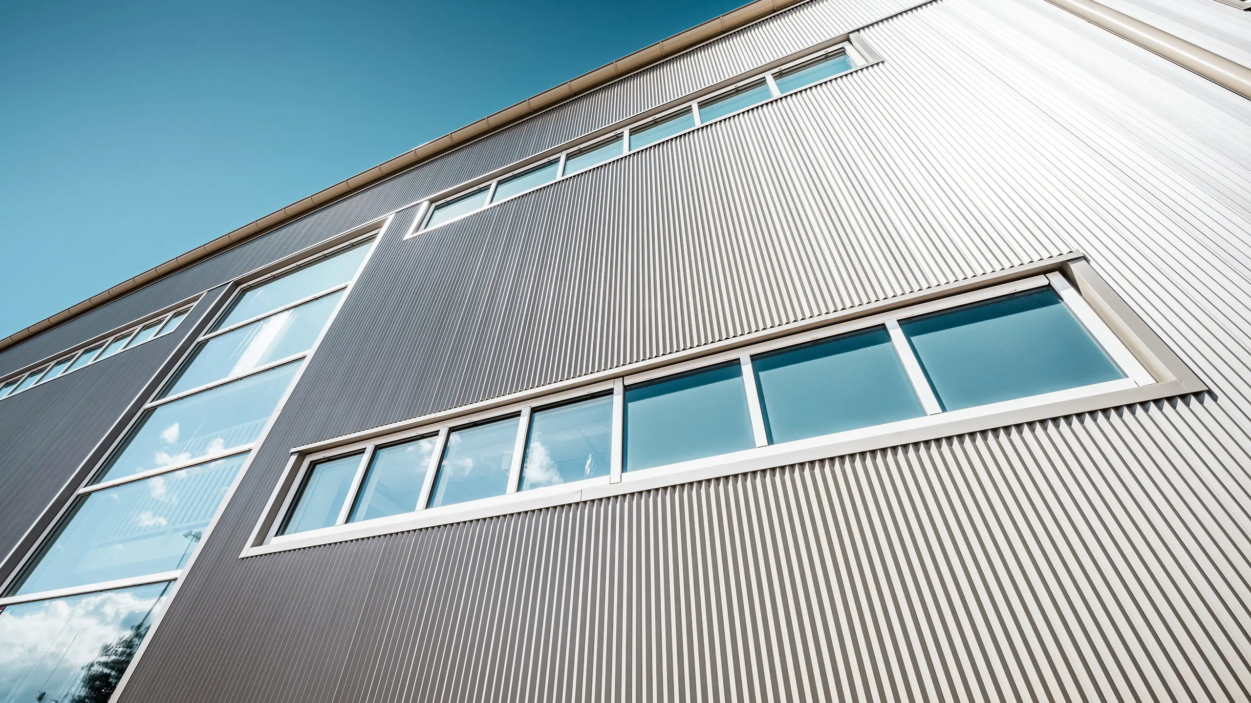Buitenkant van de Park Arena in Värnamo, Zweden, met een moderne PREFA gevel in brons. De kartelprofielen van aluminium zorgen voor opvallende licht- en schaduweffecten. De ingebouwde ramen passen harmonieus in de nauwkeurig afgewerkte gevel, die staat voor duurzaamheid, weerstand en een eigentijds design.