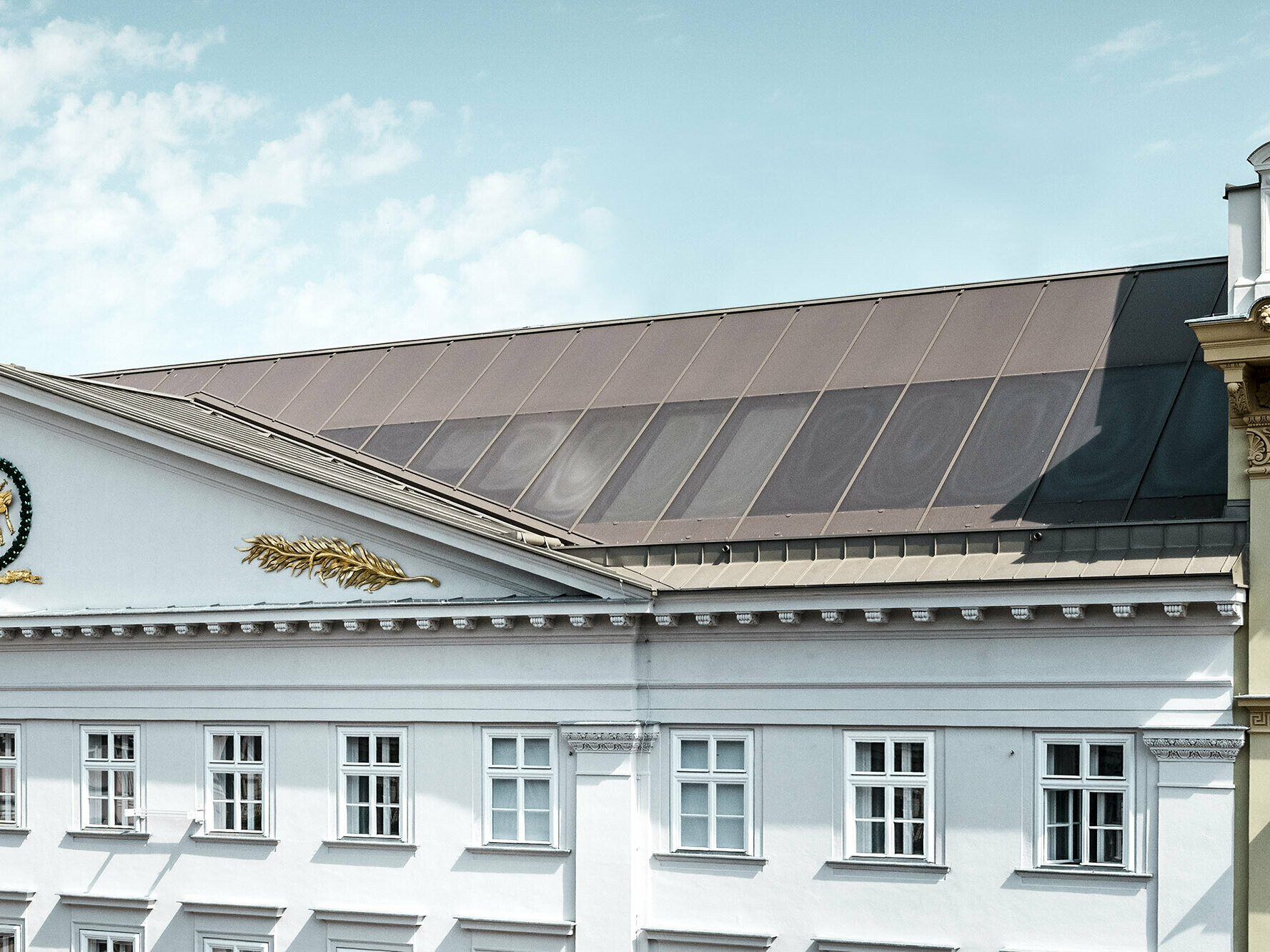 Detailansicht mit einem Teil der Fassade und dem Prefalz Dach samt siebbedruckten Gläsern.