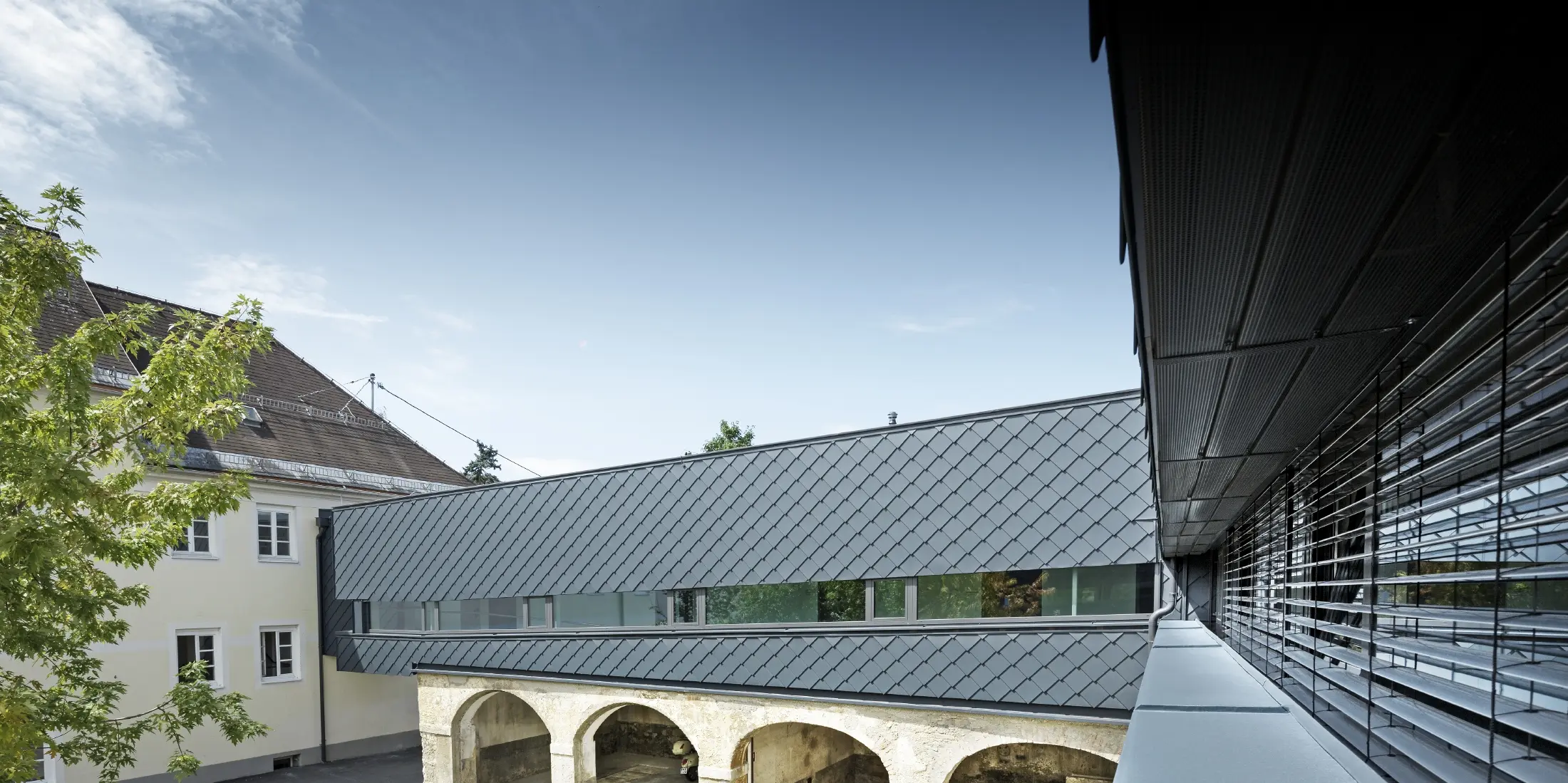 Historisch beschermd gebouw waarvan de verdieping bekleed werd met PREFA gevellosanges 29 in antraciet. Daardoor harmoniëren de oude structuren op de benedenverdieping perfect met de nieuwe losanges.