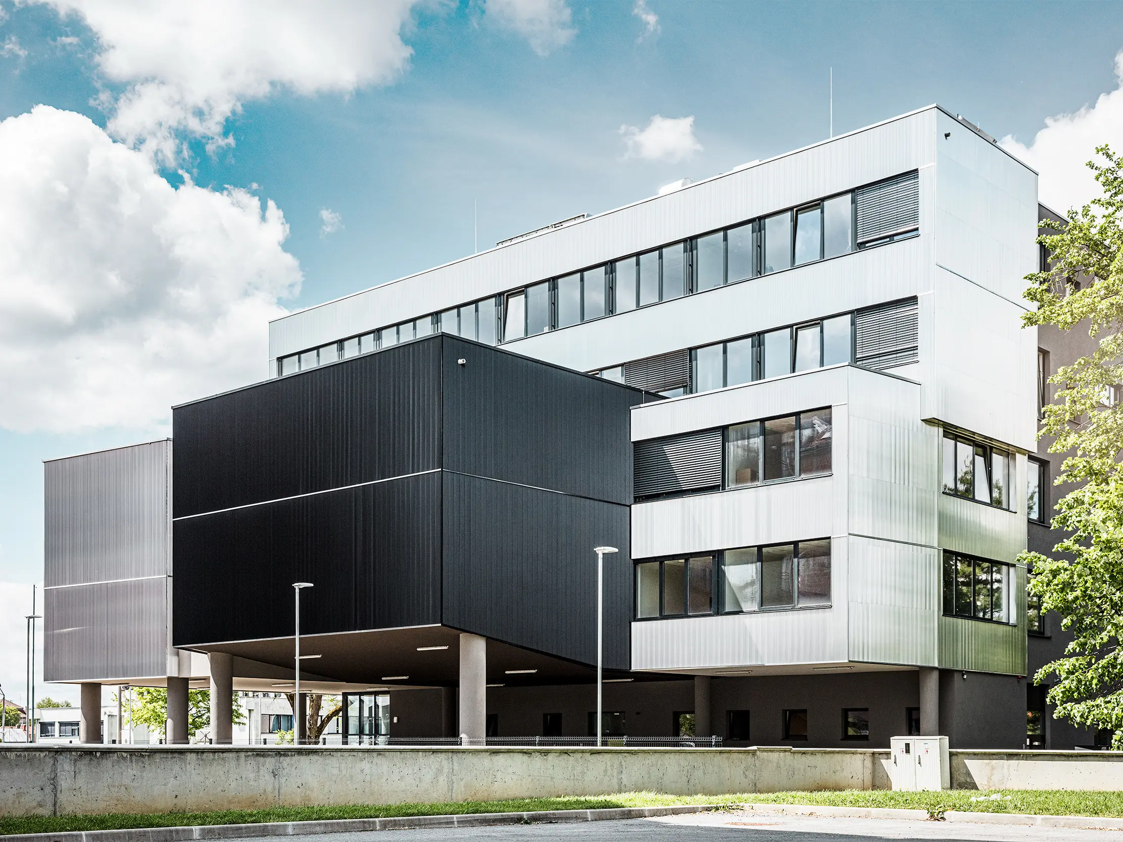 Zijaanzicht van de muziekschool in Bjelovar met een moderne PREFA-gevel inclusief kartelprofiel. De gevel werd uitgevoerd in zwart en aluminium blank, en de geometrische vormen zorgen voor een opvallend, minimalistisch design.