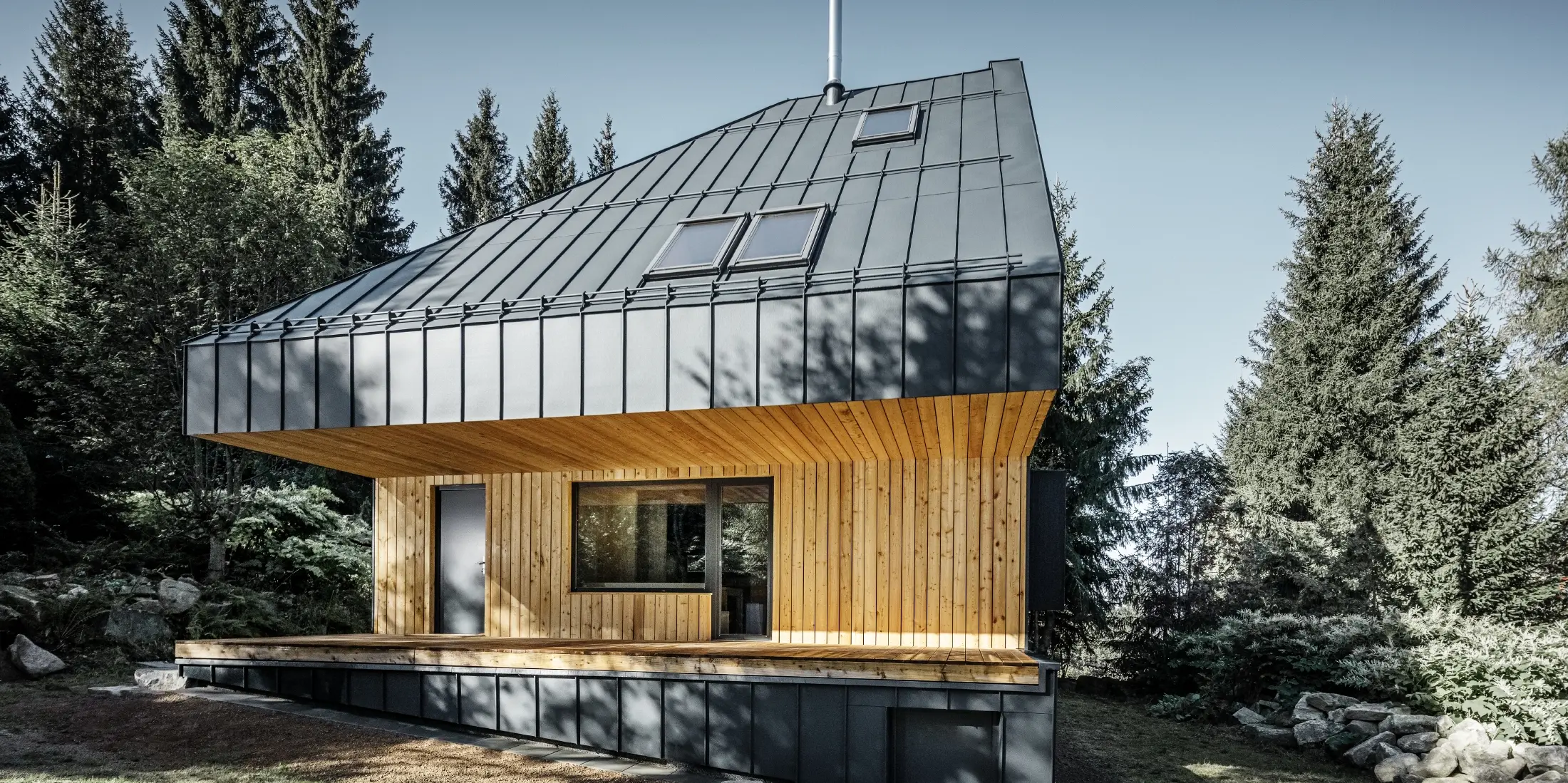 Architectonisch vrijstaand huis in het bos, het imposante dak werd bekleed met PREFA Prefalz aluminium in antraciet. Het dakbeschot en de gevel zijn bekleed met houten panelen.