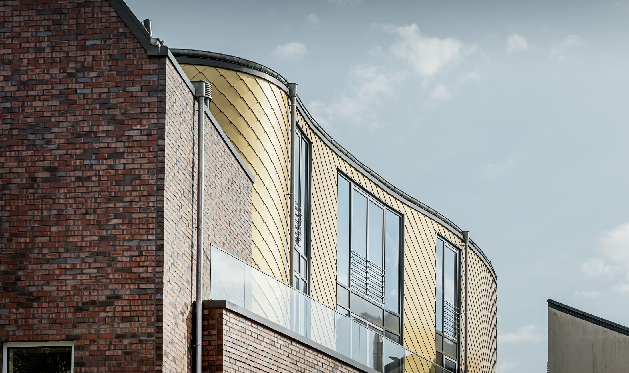 Gebogen gevel van de schoenenwinkel Schüttfort; De gevels is bekleed met de aluminium losange van PREFA in mayagoud.