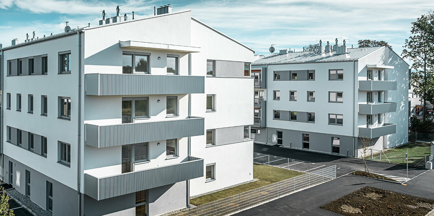 Modern woongebouw met witte gevel en balkons met PREFA kartelprofiel in zilvermetallic