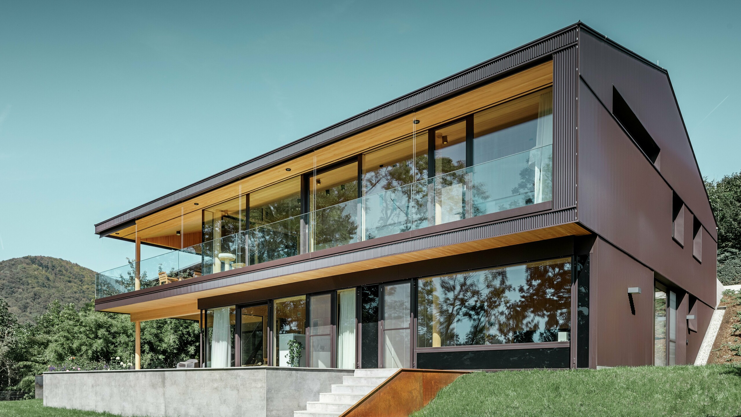 Moderne eengezinswoning met grote ramen aan de tuinzijde, de gevel is bekleed met het PREFA kartelprofiel in donkerbruin.