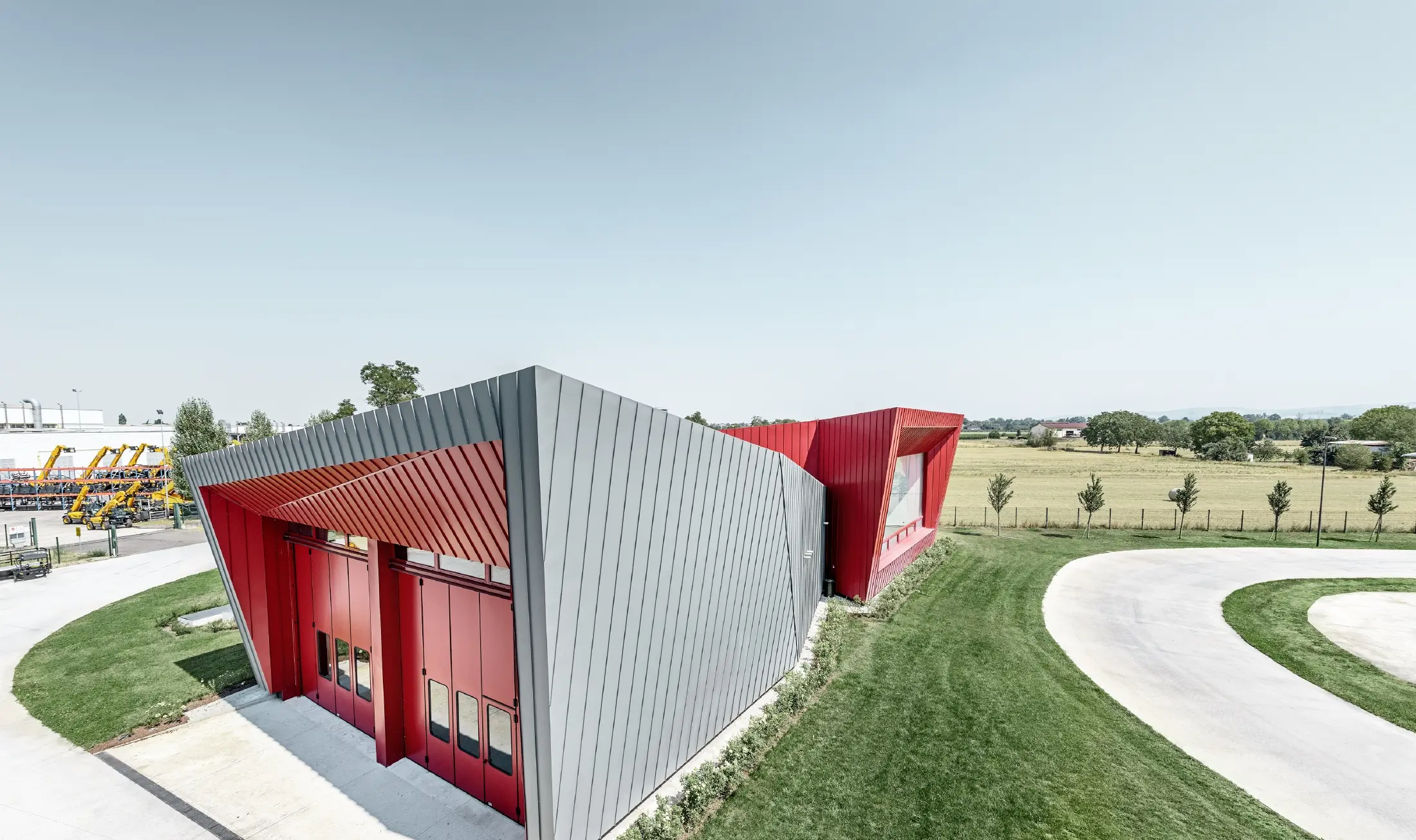 Modern opleidingscentrum van Dieci met tribune in Montecchio Emilia (Italië), bekleed met aluminium Prefalz-elementen in lichtgrijs en Falzonal-elementen in karmijnrood