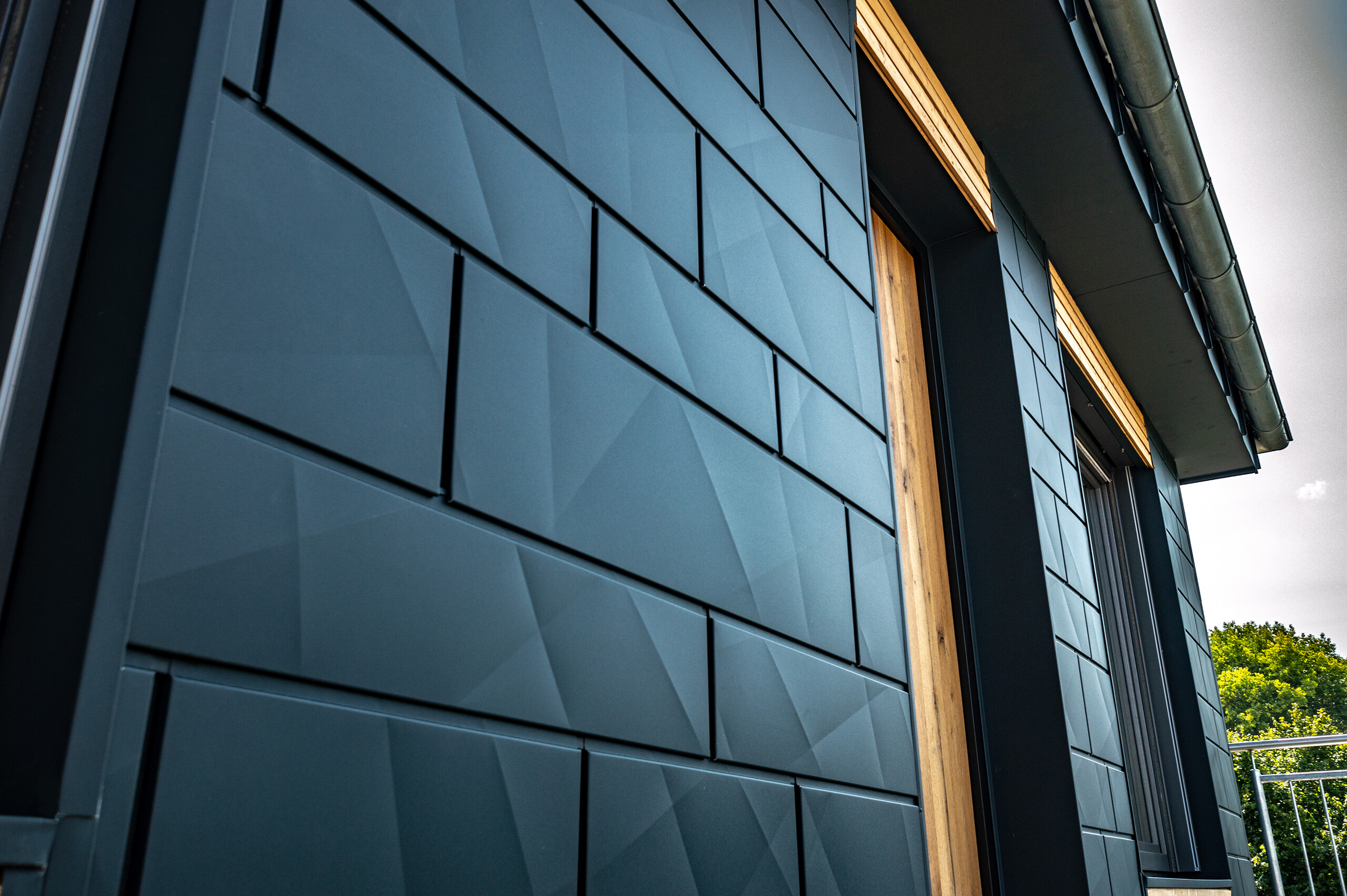 Gevel met PREFA Siding.X in antraciet met balkondeuren en grote glaspartijen gecombineerd met een houten gevel.